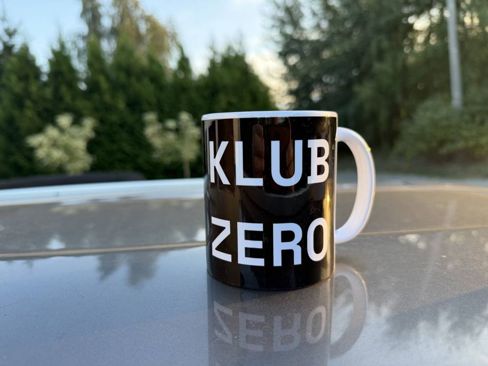 Kubek z napisem Klub Zero na stole w ogrodzie